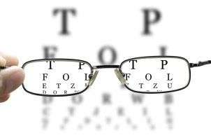 hand holding glasses to eye chart