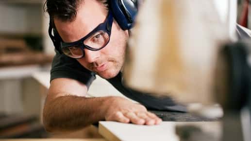 Image of a man wearing goggles while cutting wood.